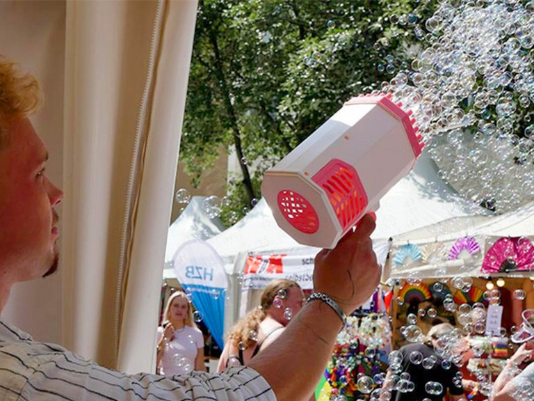 Ein Mitarbeiter der Immanuel Albertinen Diakonie sprüht mit einer Seifenblasenkanone in der Hand zahlreiche Seifenblasen in die Luft beim lesbisch-schwulen Stadtfest Motzstraßenfest rund um den Nollendorfplatz in Berlin-Schöneberg.