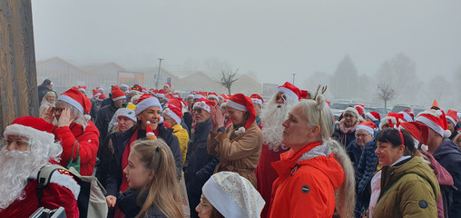 Viele Menschen mit Weihnachtskleidung stehen auf dem Parkplatz