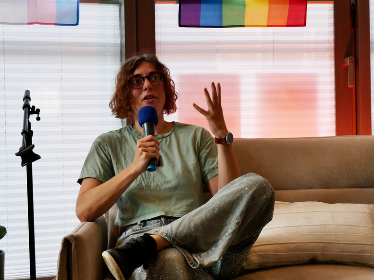 Alex M. Gastel spricht mit Mikrofon auf einer Couch