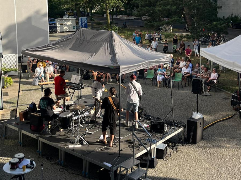 Blick auf die überachte Bühne mit einer Band vor Publikum über den Platz beim Musikfestival Fête de la Musique vor dem Immanuel Stadtteilzentrum Borsigwalde in Berlin-Reinickendorf. Blick auf die überachte Bühne mit einer Band vor Publikum über den Platz beim Musikfestival Fête de la Musique vor dem Immanuel Stadtteilzentrum Borsigwalde in Berlin-Reinickendorf.