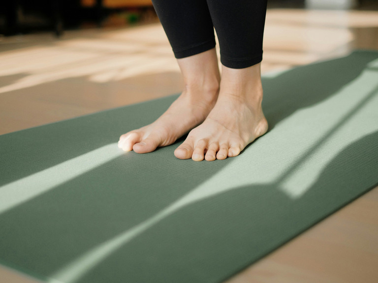 Füße stehen auf einer Yoga-Matte