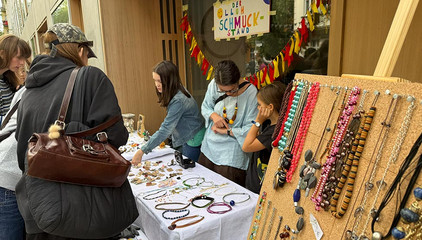 Mehrere Menschen stehen an einem Flohmarktstand mit einem Tisch und Aufsteller mit Schmuck und Ketten beim 7. Zelterstraßenfest mit der Immanuel Beratung Prenzlauer Berg in Berlin. Mehrere Menschen stehen an einem Flohmarktstand mit einem Tisch und Aufsteller mit Schmuck und Ketten beim 7. Zelterstraßenfest mit der Immanuel Beratung Prenzlauer Berg in Berlin.