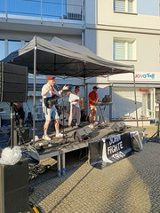 Eine Band spielt auf einer überdachten Musikbühne auf einem gepflasterten Platz beim Musikfestival Fête de la Musique vor dem Immanuel Stadtteilzentrum Borsigwalde in Berlin-Reinickendorf.