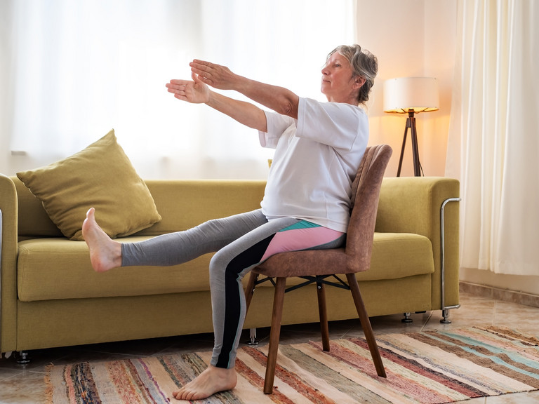 Frau sitzt auf Stuhl und macht Stuhlyoga