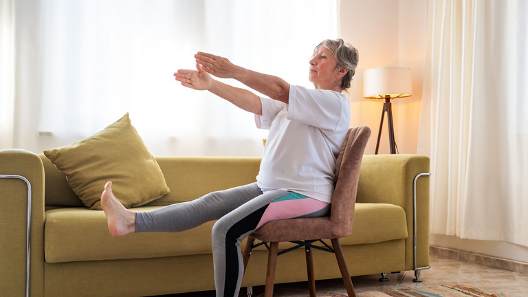 Frau sitzt auf Stuhl und macht Stuhlyoga